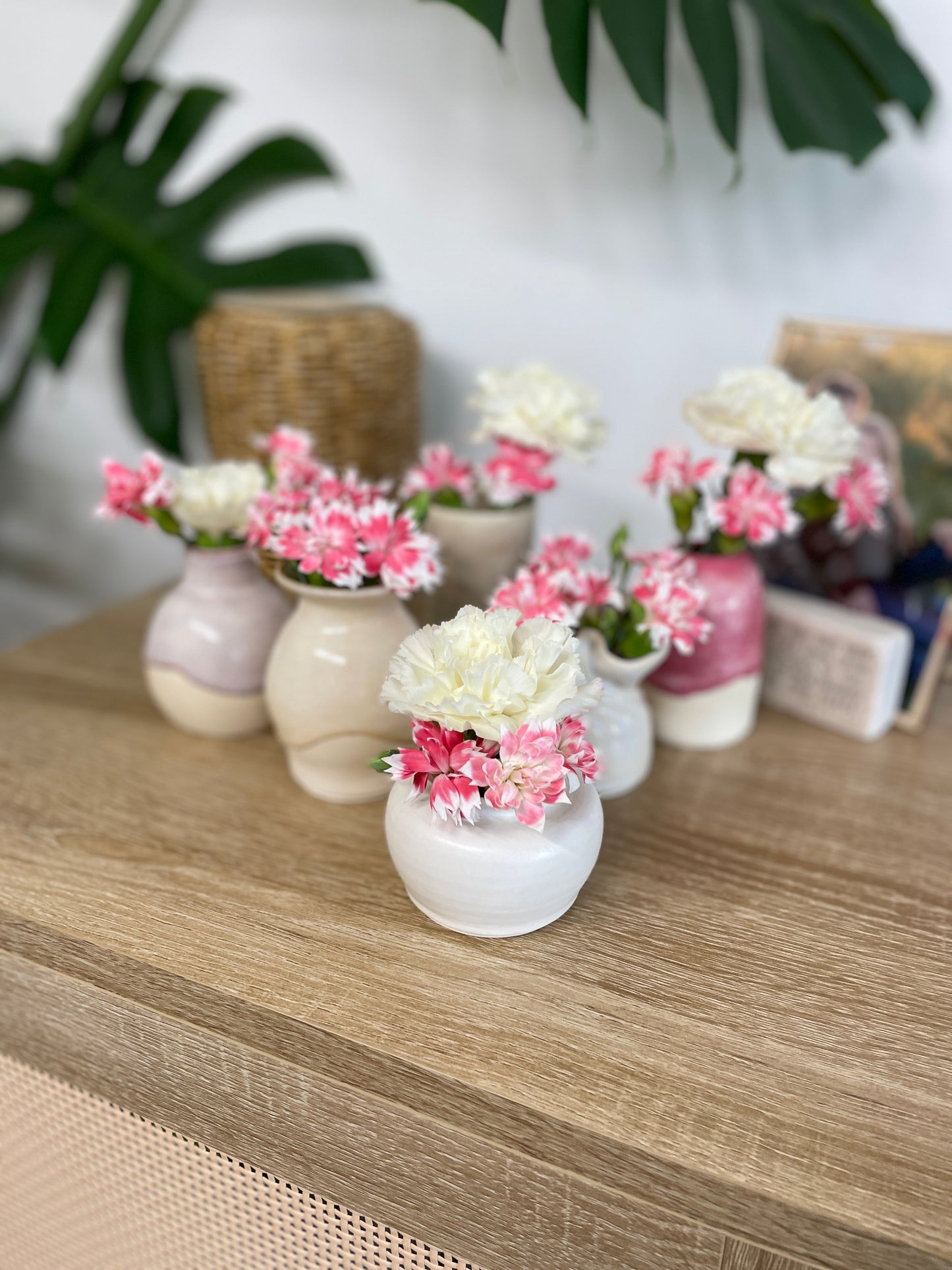 Various small ceramic bud vases holding pink and white flowers