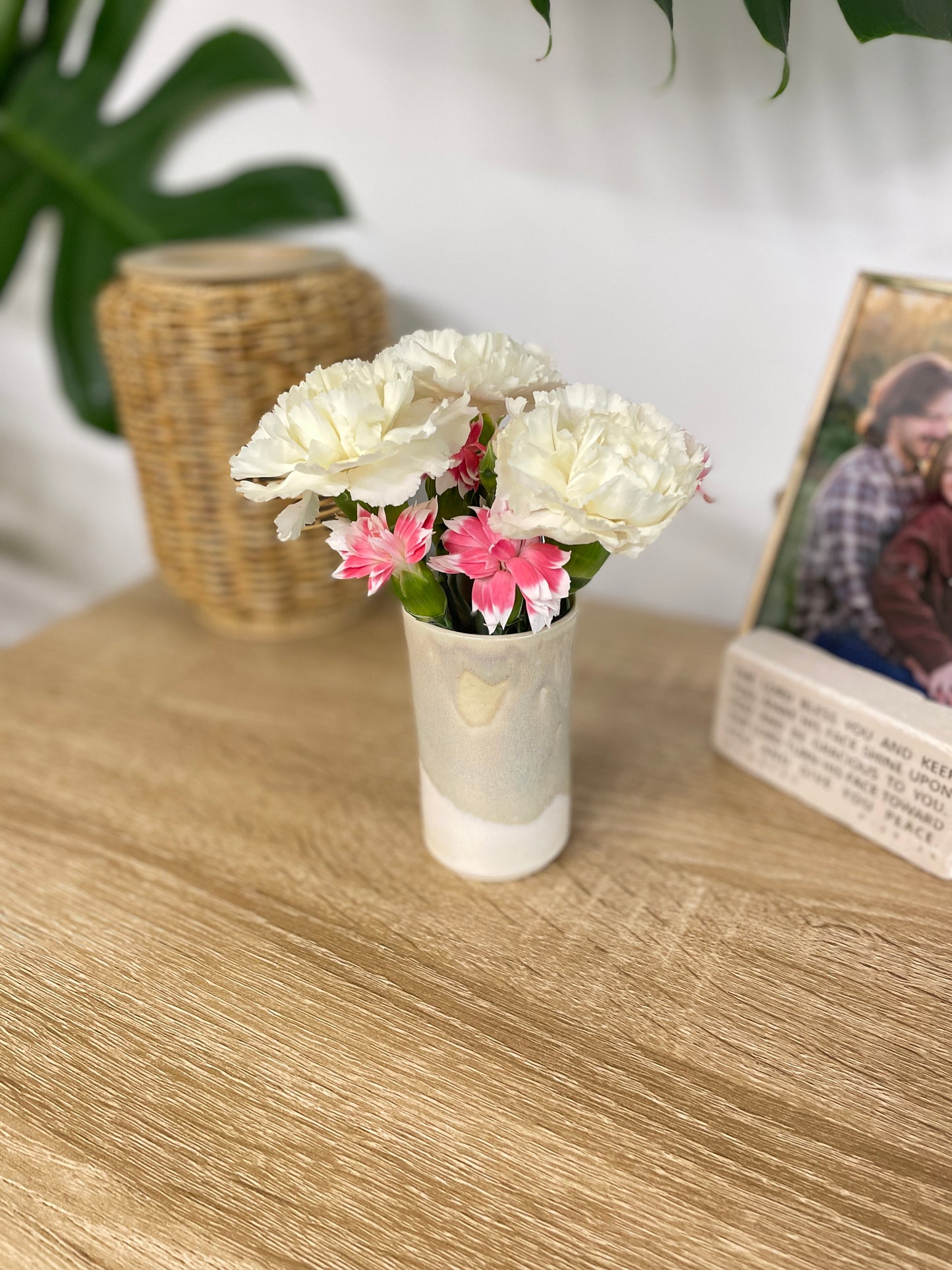 Light sage green and eggshell colored small ceramic bud vase holding white and pink flowers