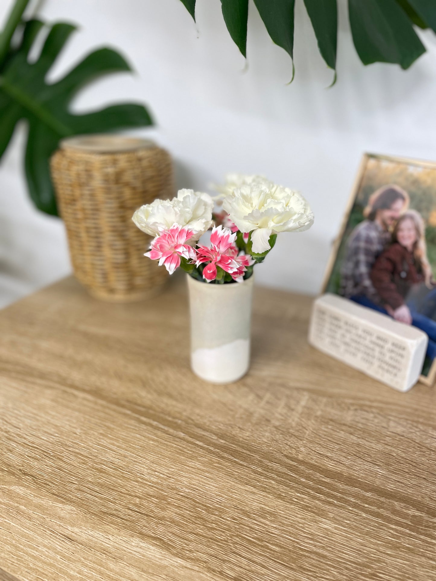 Light sage green and eggshell colored small ceramic bud vase holding white and pink flowers