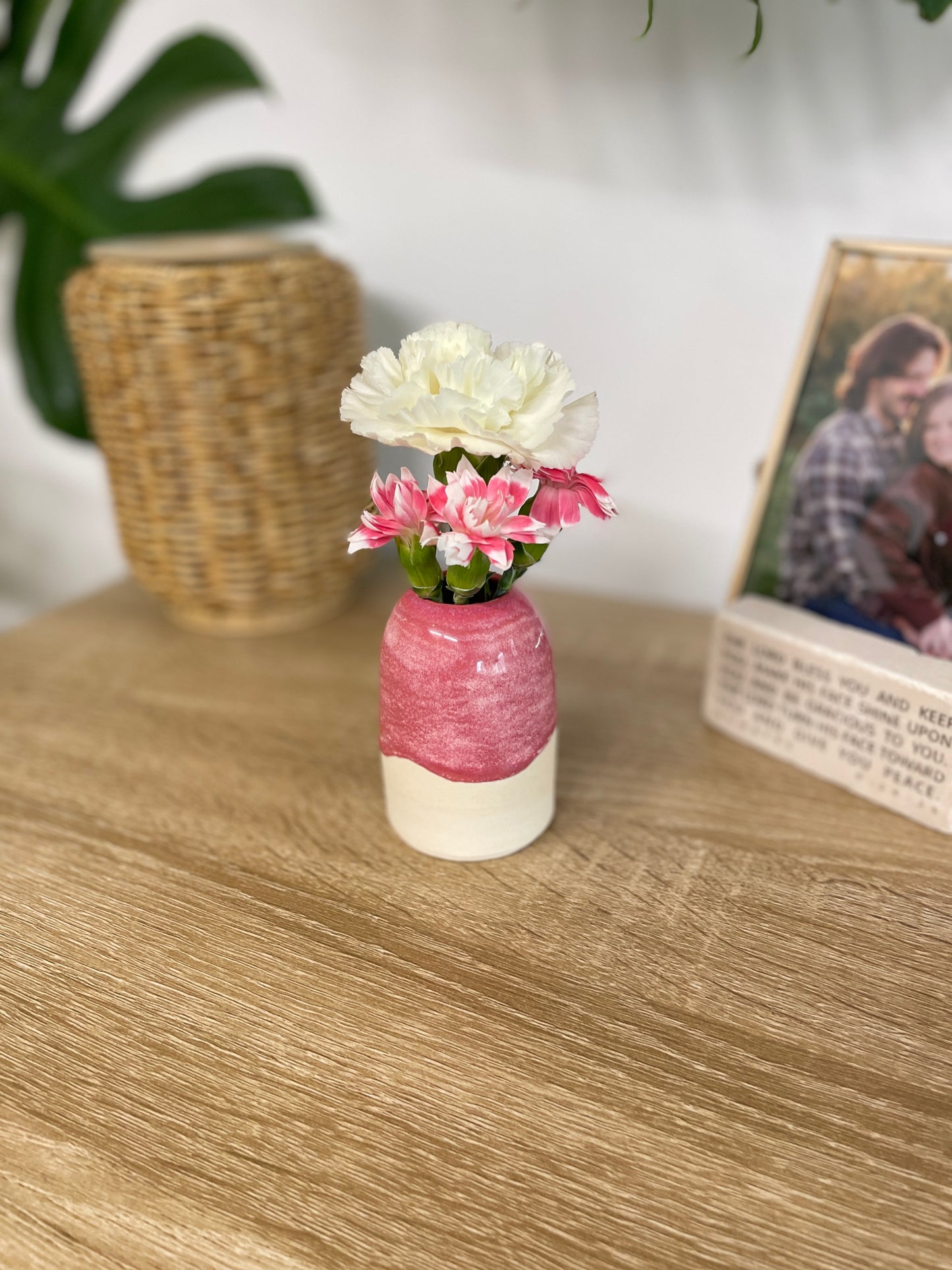 Hot pink colored small ceramic bud vase holding pink and white flowers