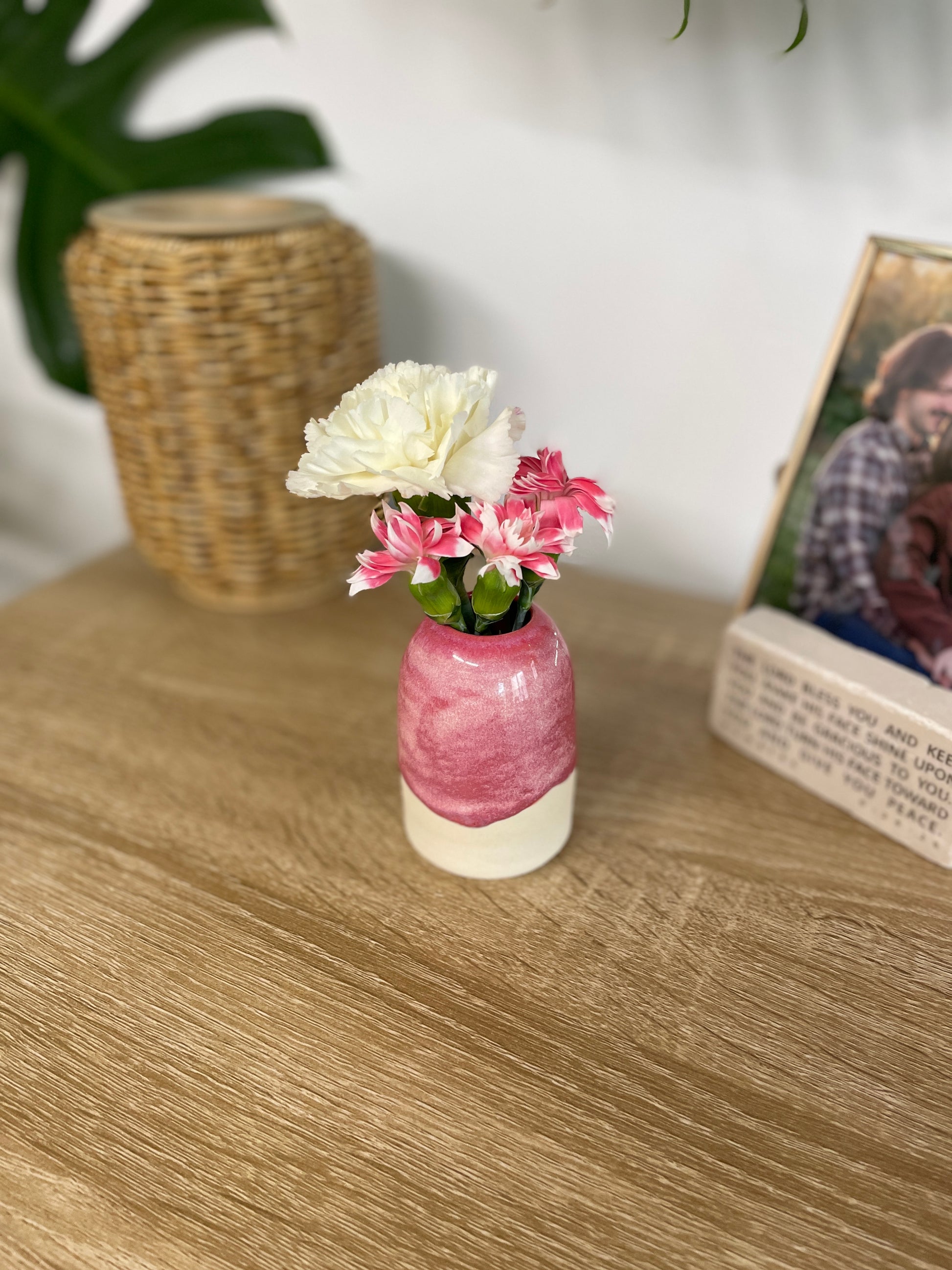 Hot pink colored small ceramic bud vase holding pink and white flowers