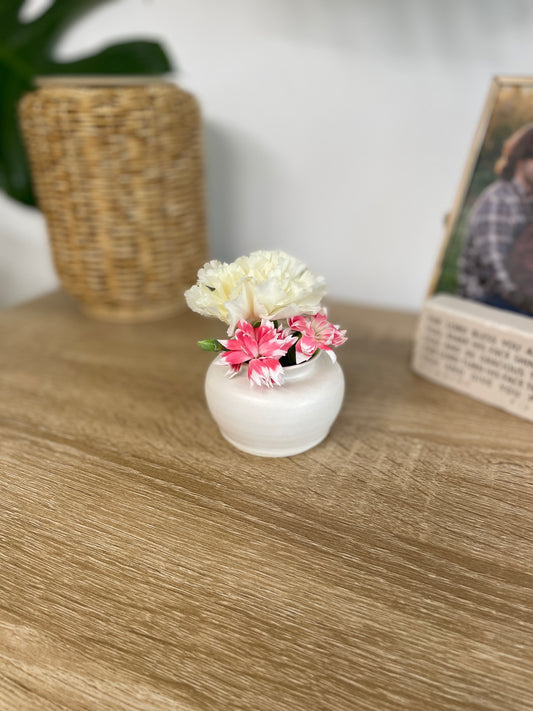 Matte white colored small ceramic bud vase holding white and pink flowers