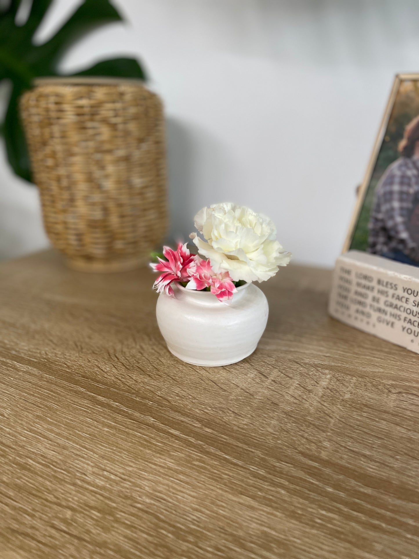 Matte white colored small ceramic bud vase holding white and pink flowers